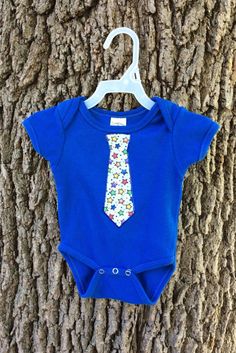 Hand decorated bodysuit.  This bodysuit features a tie on it.  Your little boy can look dressed up no matter the occasion! The tie decal is made from fabric and outlined with fabric paint.  Although pictured on a blue bodysuit, this would look adorable on any color!  I can create the tie with any color fabric - just ask! If you have any questions about this bodysuit, please let me know so I can assist you! Remember, as these items are handmade, each will be unique.  Although it may not arrive EX Blue Fitted Cotton Short Sleeve Bodysuit, Fitted Blue Bodysuit For Playtime, Fitted Blue Short Sleeve Bodysuit For Playtime, Summer Party Fitted Onesie, Fitted Summer Party Onesie, Cute Fitted Bodysuit For Playtime, Playful Fitted Bodysuit For Playtime, Spring Playtime Fitted Onesie, Blue Fitted Bodysuit For Playtime