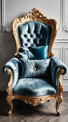 an ornate blue chair with gold trimmings in front of a white wall and wooden floor