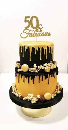 a black and yellow birthday cake with white frosting on the top that says 50 fabulouss