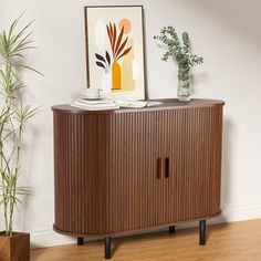 a wooden cabinet sitting on top of a hard wood floor next to a potted plant