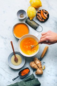 the ingredients to make this soup are laid out on a marble counter top, including carrots and ginger