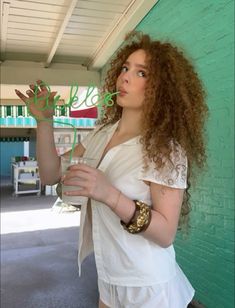 a woman with curly hair holding a drink