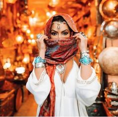 a woman wearing a red scarf and headdress standing in front of a store display