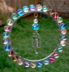 a circular glass ornament hanging from a metal ring with colorful beads on it