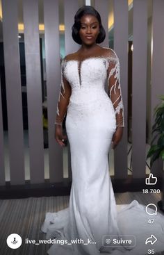 a woman in a white wedding dress standing next to a plant and looking at the camera