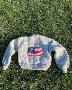 a sweater with an american flag on it is laying in the grass and looking down