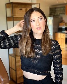 a woman in a black top is posing for the camera with her hand on her head