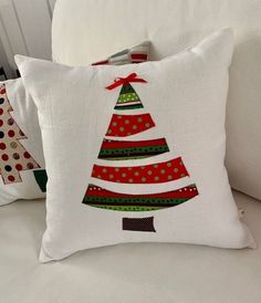 two pillows with christmas trees on them are sitting on a couch next to each other