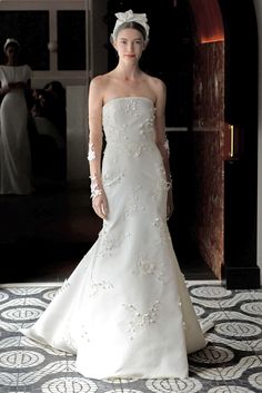 a woman in a white wedding dress standing on a tile floor