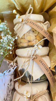 three jars filled with cookies sitting on top of each other next to flowers and wrapped in brown paper