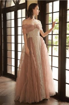 a woman standing in front of a window wearing an off the shoulder dress