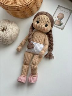 a knitted doll sitting on top of a table next to a ball of yarn