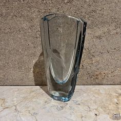 a clear glass vase sitting on top of a marble counter next to a stone wall