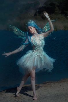 a woman dressed as a fairy dancing on the beach