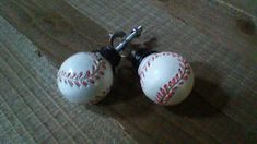 two white baseballs with red stitching on them sitting on a wooden floor next to each other