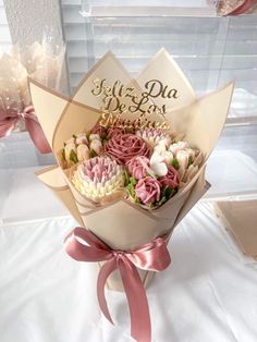 a bouquet of flowers sitting on top of a white table next to some pink ribbon