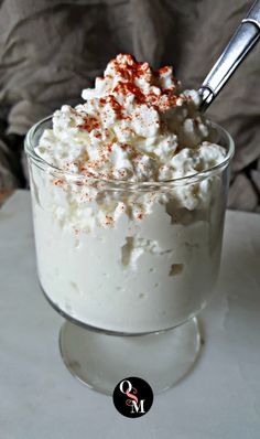 a glass bowl filled with whipped cream and sprinkles on top of a table