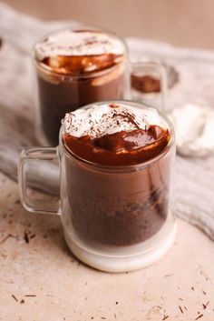 two mugs filled with hot chocolate and marshmallows on top of a table