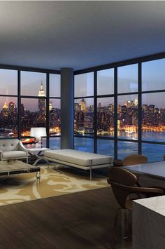 a living room filled with furniture and large windows overlooking the city at night in front of them