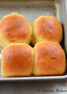 four rolls sitting in a metal pan on top of a counter