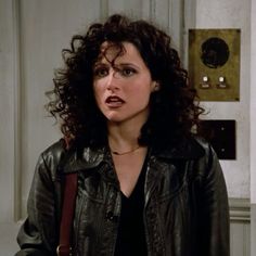 a woman with curly hair wearing a black leather jacket