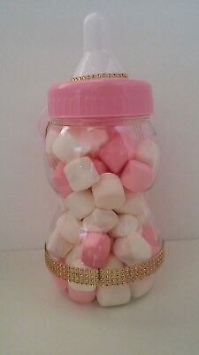 pink and white marshmallows in a glass jar with gold trim around the lid