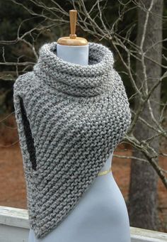 a gray knitted shawl on a mannequin with trees in the background