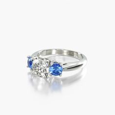 two stone engagement ring with blue and white stones on the sides, set in 18k white gold