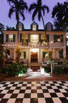 a large white house with black and white checkered flooring in front of it