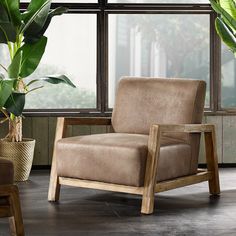 a brown chair sitting in front of a window next to a potted green plant