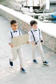 two young boys dressed in formal clothes holding a sign