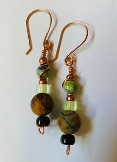 Fall colors of green, brown, earth tone bead with colors of reds, orange, black, dark blue, copper seed bead accents, dark brown doughnut bead at the bottom with handcrafted french ear wires. Earth Tone Jewelry, Earrings Funky, Bead Dangles, Earrings Bead, Wire Earring, Brown Agate, Bohemian Style Jewelry, Earthy Jewelry, Funky Design