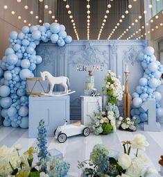 a blue and white themed party with balloons, flowers, and a horse figurine