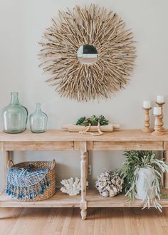 a wooden table topped with lots of vases next to a wall mounted sunburst