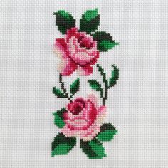 two pink roses are on the side of a cross - stitched wall hanging in front of a white background