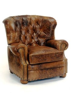 a brown leather chair with studding on the armrests and foot rests against a white background