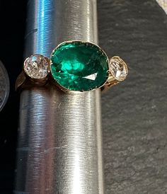 "Antique 14K classic Diamond and I believe Emerald man made paste ring.  Size 4 3/4, wt.- 2.6 grams, top of ring approx. 1/3\" by 2/3\".  Condition is very good for it's age any slight wear commensurate with age-photos show the details.. Super entering gold setting with wonderful rich Emerald green color stone flanked by two old world cut white Diamonds(approx. 45 pt total wt for two Diamonds), lots of intriguing look to this beauty.  Tests for 14k.  Unique timeless design." Victorian Oval Emerald Ring In Yellow Gold, Victorian Oval Yellow Gold Emerald Ring, Antique Yellow Gold Emerald Ring With Diamond, Antique Emerald Ring With Diamond In Yellow Gold, Antique Emerald Ring In Stamped 14k Yellow Gold, Victorian Emerald Ring In Yellow Gold Stamped 14k, Victorian Emerald Ring In 14k Yellow Gold, Yellow Gold Emerald Ring With Rose Cut Diamonds, Oval Gold Emerald Ring With Rose Cut Diamonds