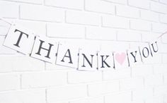 a thank you sign hanging on a brick wall next to a pink heart shaped balloon