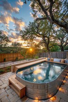 an outdoor hot tub with steps leading up to it and the sun setting in the background