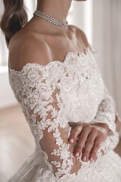 a woman in a white wedding dress holding her hand on her shoulder