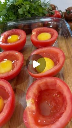 tomatoes with eggs in them sitting on a cutting board