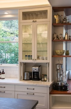 a kitchen with white cabinets and glass doors