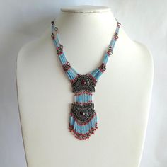 Stunning vintage light blue and red glass bead multi strand fringe bib necklace. Made of light blue and red glass seed beads with two gray embossed pendants with red rhinestone centers. Graduated multi strand beaded linked with lobster claw clasp and extender chain. Great vintage condition with light tarnish. High quality made with nice weight. Unsigned. Size: 17" to 20" x 4" x 1.5" wide. Thank you for visiting our shop! Please refer to photos as part of the description. Please Check out FAQs an Bohemian Turquoise Necklaces With Bead Caps, Blue Bohemian Beaded Necklaces With Bead Caps, Bohemian Turquoise Necklace With Bead Caps, Blue Bohemian Beaded Necklaces, Bohemian Silver Beaded Necklaces With Bead Caps, Traditional Blue Jewelry With Bead Caps, Blue Bohemian Necklaces With Bead Caps, Silver Bohemian Beaded Necklaces With Bead Caps, Silver Bohemian Beaded Necklace With Bead Caps