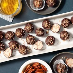 chocolates and nuts are on plates next to cups