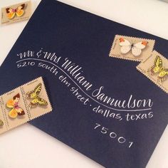 two stamps with butterflies on them are next to a blue envelope