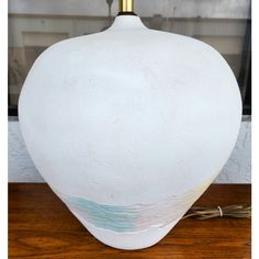 a white vase sitting on top of a wooden table