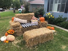 hay bales and pumpkins are arranged on the lawn