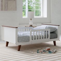 a white crib with a book on the floor and a window in the background