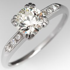 This timeless vintage engagement ring is centered with an old European cut diamond weighing 1.02 carats and set into a four-prong head. The shoulders of the ring are each accented with three (3), channel set, round single cut diamonds, bordered with milgrain edging. The ring measures 6.7mm at the top, rises 6.3mm above the finger, tapering to 1.3mm wide and 1.1mm thick at the base of the shank. The ring is currently a size 7.25 and we offer complimentary resizing to fit. Classic Style Ring With Single Cut Diamonds, Classic Cushion Cut Diamond Ring With Single Cut Diamonds, Classic Gia Certified White Diamond Ring, Vintage Gia Certified White Diamond Ring, Vintage Gia Certified Diamond Ring, Vintage Gia Certified Diamond Ring With Round Band, Classic Gia Certified Cushion Cut Rings, Classic Gia Certified Cushion Cut Diamond Ring, Classic Cushion Cut Single Diamond Wedding Ring