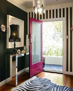 a zebra print rug on the floor in front of a pink door with a black and white striped wall